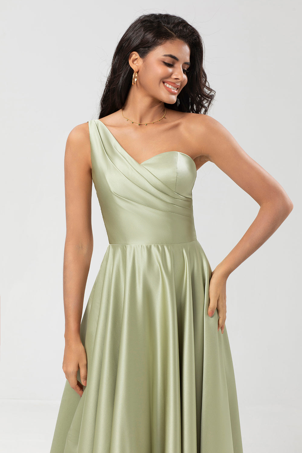 Un vestido de dama de honor verde satinado de hombro con bolsillos