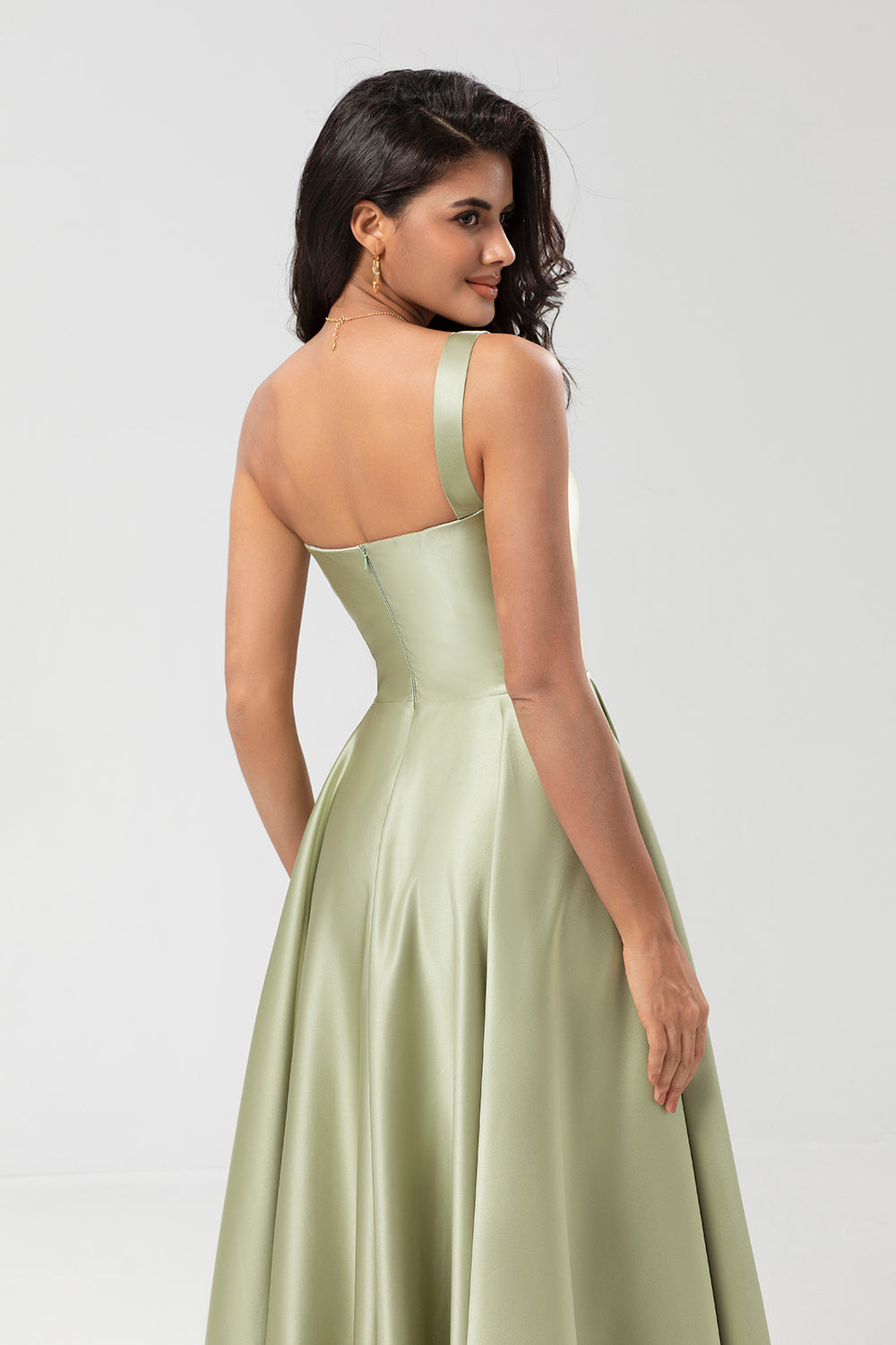 Un vestido de dama de honor verde satinado de hombro con bolsillos