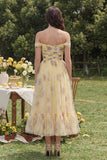 Vestido midi de flor amarilla con línea A y hombros descubiertos con volantes