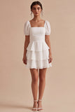 Una línea de vestido mini blanco con volantes y escote cuadrado con mangas abullonadas