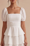 Una línea de vestido mini blanco con volantes y escote cuadrado con mangas abullonadas