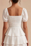 Una línea de vestido mini blanco con volantes y escote cuadrado con mangas abullonadas