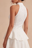 Un vestido mini blanco con volantes de escaleras con capas de lentejuelas y lentejuelas